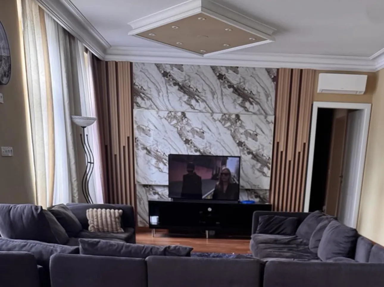 TV-Wand nach Maß mit Marmoroptik und Holzlamellen in einem Wiener Wohnzimmer